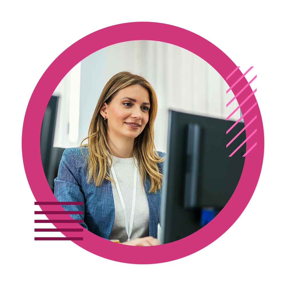 Woman looking at the computer in an office, smiling.