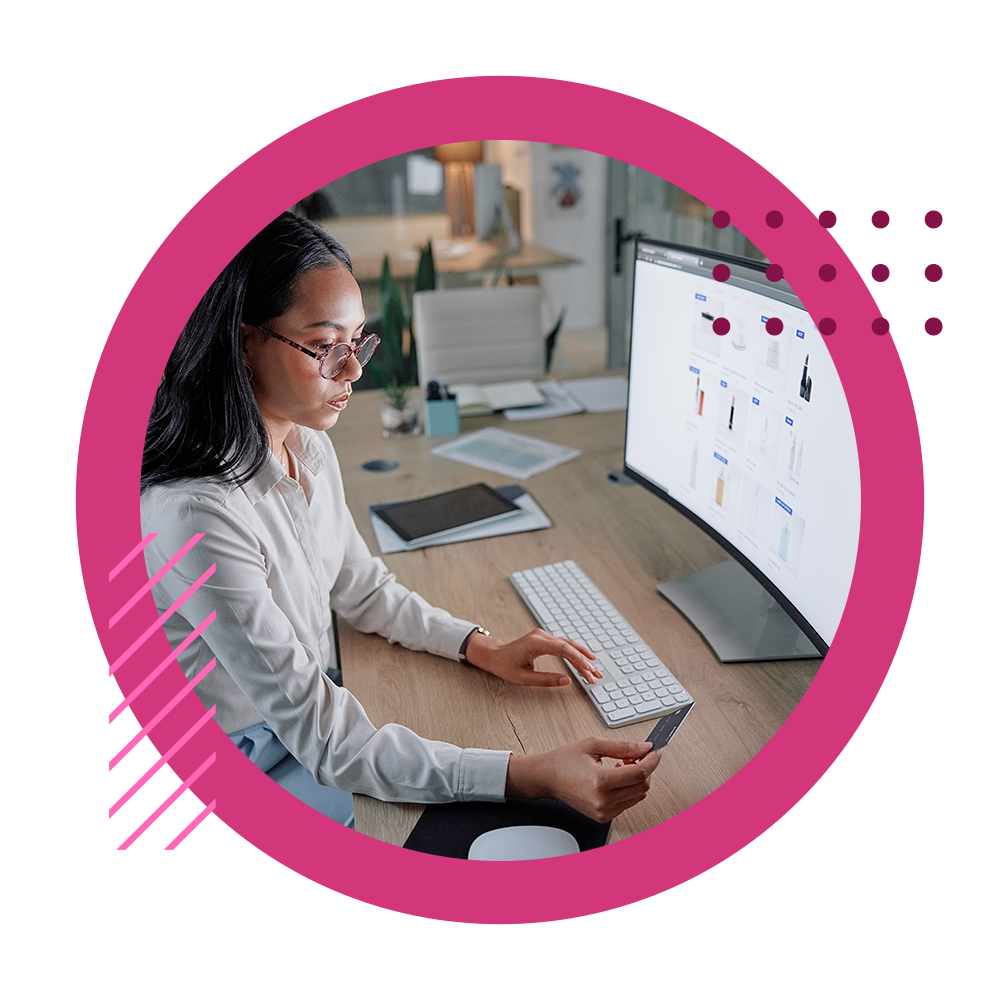 A business woman looking at her credit card to make a purchase at her desktop monitor on a B2B ecommerce website.